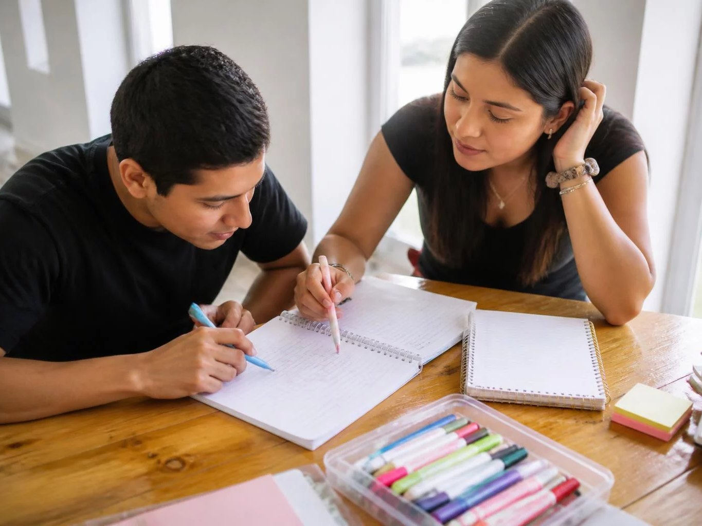 Dos participantes trabajando juntos con cuaderno y plumones